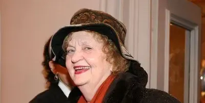Татяна Лолова  с часовник върху шапката си и стикер за инвалиди на колата си