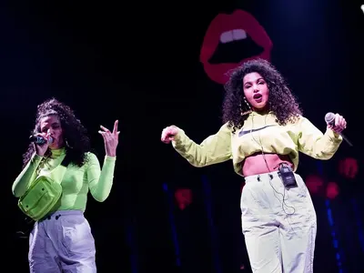 Едната близначка пее с чанта на гърдите